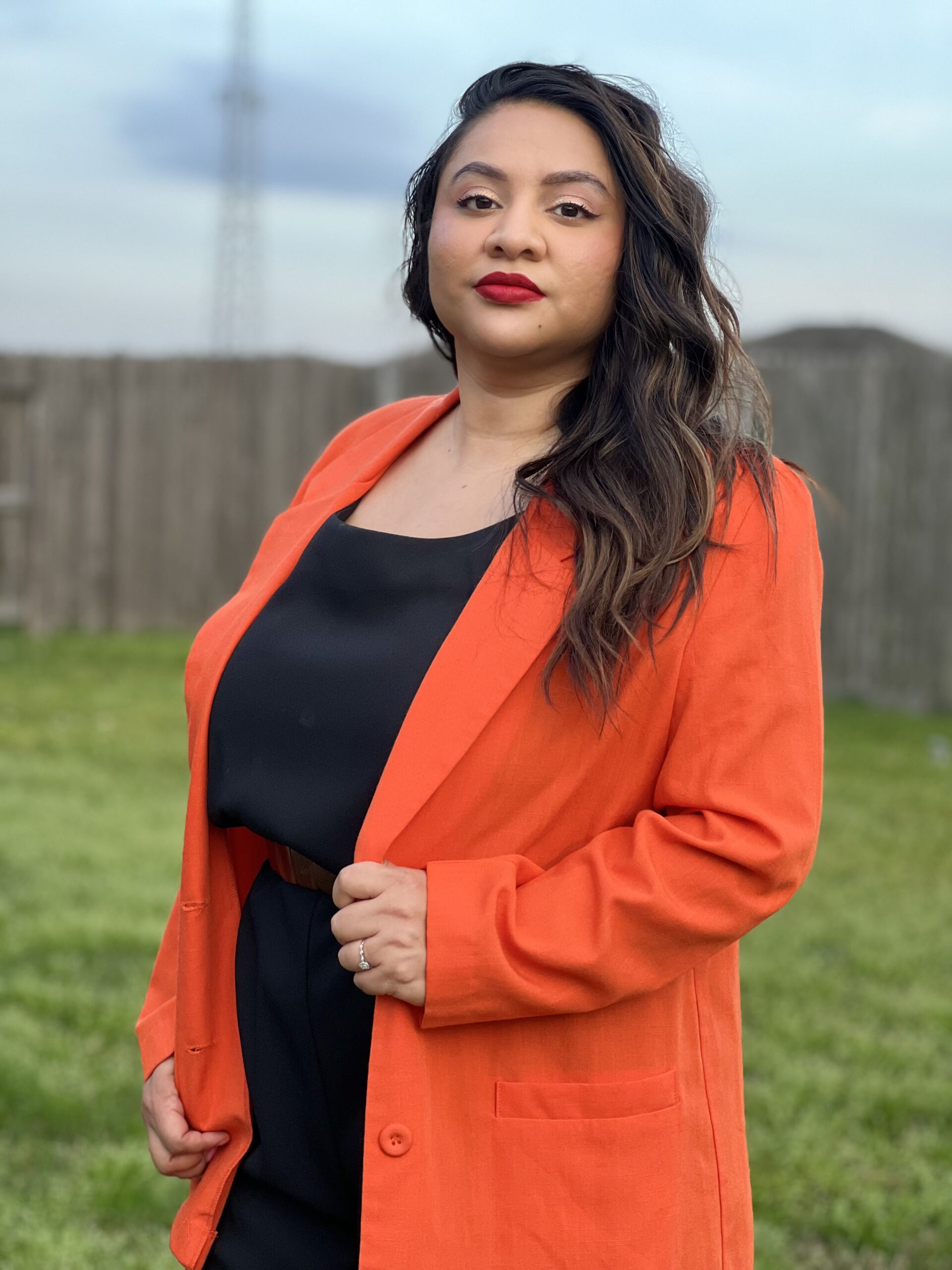 Stephanie Gonzalez headshot: A woman with dark hair and an orange suit jacket